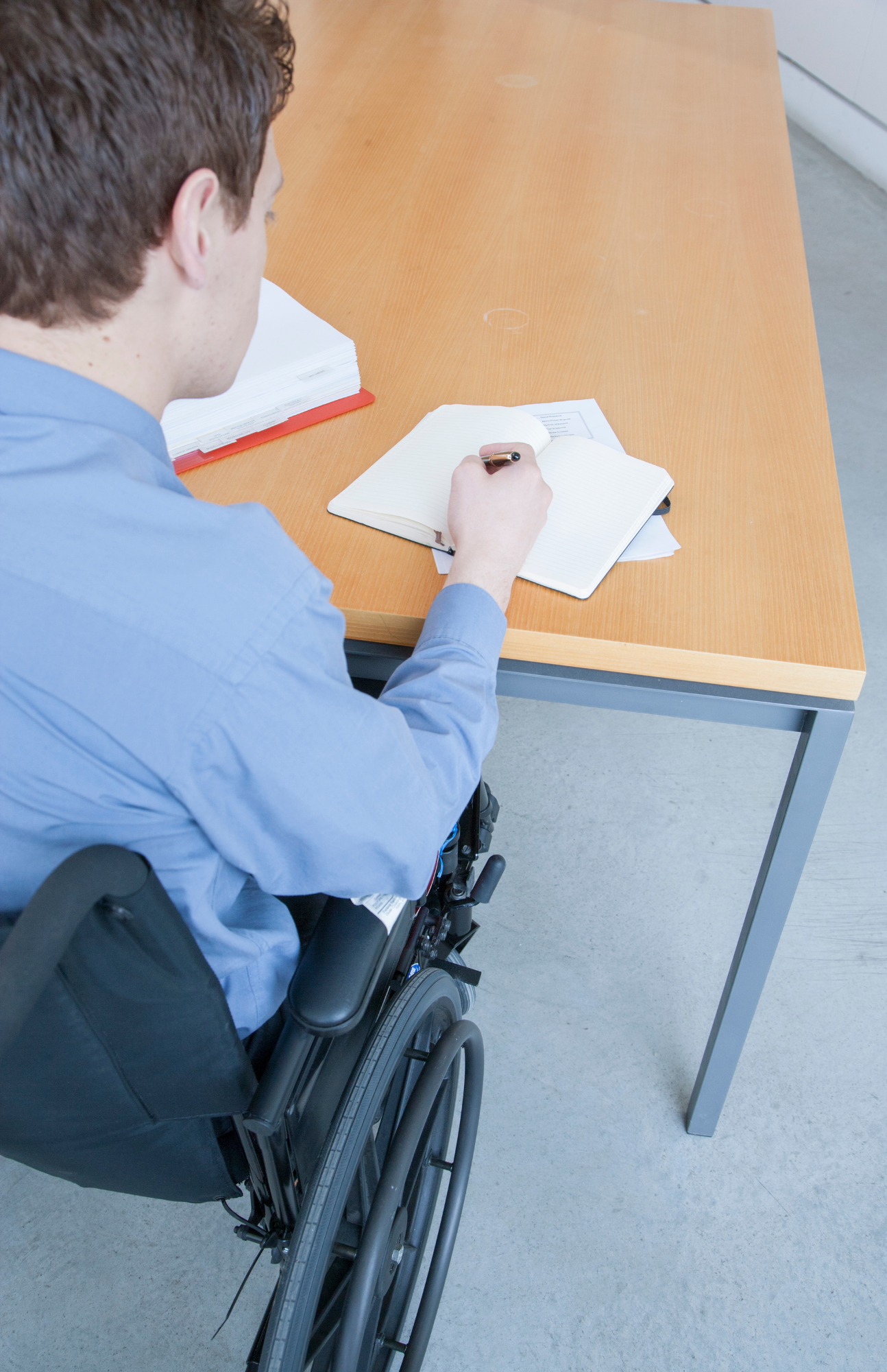 man in wheelchair filing out paperwork. 